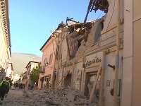 Hasiči pred zničenou budovou po zemetrasení v talianskej Norcii.