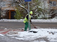 Pracovník Správy mestských komunikácií odpratáva sneh z chodníkov. 
