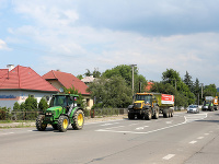 Kolóna strojov s transparentmi počas protestnej jazdy farmárov na traktoroch.