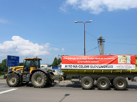 Kolóna strojov s transparentmi počas protestnej jazdy farmárov na traktoroch.
