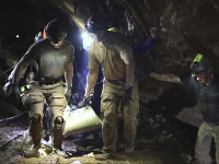 Fotografia ukazuje záchranárov, ako vyvádzajú jedného z chlapcov vnútri jaskyne.