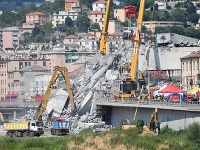  Hasiči s ťažkými mechanizmami pracujú na odstraňovaní trosiek z diaľničného mosta Morandi  