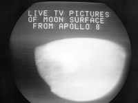 Fototografia zobrazuje televíznu obrazovku s pohľadom na mesiac vysielaný astronautmi Apollo 8