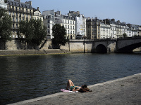 Žena sa opaľuje na brehu rieky Seina počas slnečného a teplého počasia v Paríži