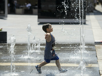 Dieťa sa ochladzuje vo fontáne počas horúčav 
