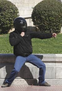 Demonštrant zameriava svoj prak na políciu počas štrajku v Aténach