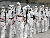 Vojaci juhokórejskej armády, ktorí nosia ochranné vybavenie, sa zhromažďujú, aby nasprejovali dezinfekčný prostriedok.
