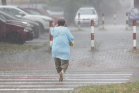 Na snímke žena prechádza cez ulicu počas búrky a silného dažďa v Podunajských Biskupiciach v Bratislave.