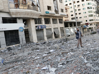 Ľudia sledujú trosky zničenej kliniky zdravotnej starostlivosti v blízkosti ministerstva zdravotníctva v Gaze po izraelskom nálete na horné poschodia budovy.