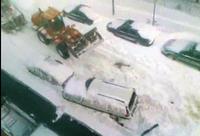 Odhŕňač snehu odchádza. Zničené auto si nevšíma.