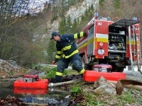 Hasiči čerpajú vodu z potoka do cisterny počas zásahu proti lesnému požiaru.