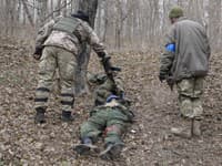 Ukrajinskí vojaci si prezerajú telá mŕtvych ruských vojakov.