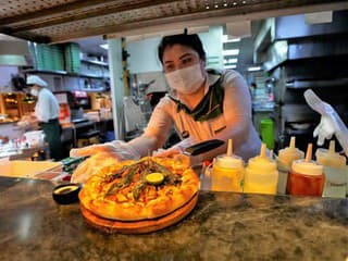 Zamestnankyňa ukazuje pizzu s