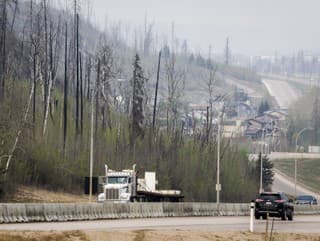 Doprava sa presúva po diaľnici Alberta Highway 63, keď vo vzduchu visí dym z lesného požiaru v meste Fort McMurray v štáte Alta v stredu 15. mája 2024.