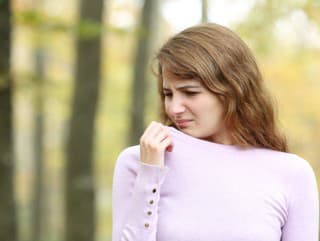 Disgusted woman smelling clothes
