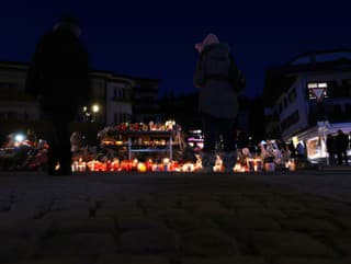 Ľudia zapaľujú sviečky a