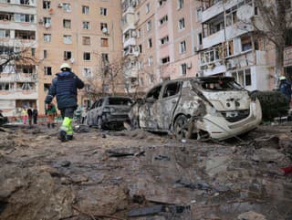 Ľudia prechádzajú okolo zničených