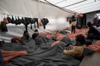 Utečenci zabalení v prikrývkach a nepremokavých vreciach ležia v sobotu 5. novembra 2022 na palube záchrannej lode Ocean Viking v Sicílskom prielive v Stredozemnom mori.