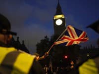 Protestujúci máva vlajkou Union Jack pred policajtmi na Parlamentnom námestí v Londýne v sobotu 11. novembra 2023 počas propalestínskeho protestného pochodu, ktorý sa koná od Hyde Parku k veľvyslanectvu USA vo Vauxhall.