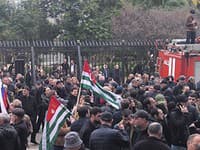 Demonštranti sa s abcházskymi zástvami zhromažďujú pred budovou abcházskeho parlamentu.
