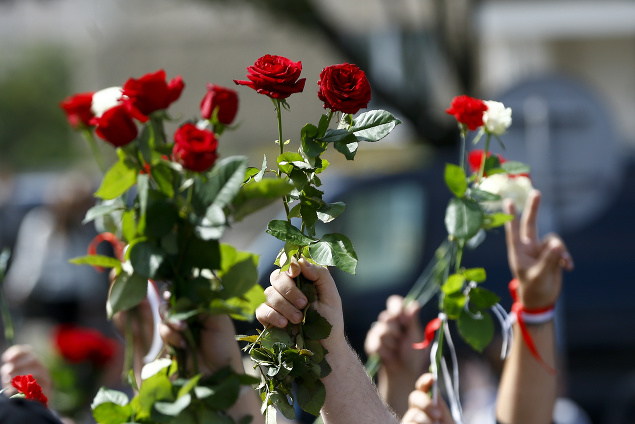 Ľudia mávajú s kvetmi počas pohrebu Alexandra Tarajkovského.