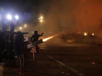 Maskovaní mladí demonštranti hádžu zápaľné fľaše a pyrotechniku pred úrad premiéra na protivládnom proteste v Tirane.