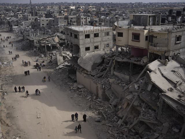 Palestínčania prechádzajú zničenými budovami