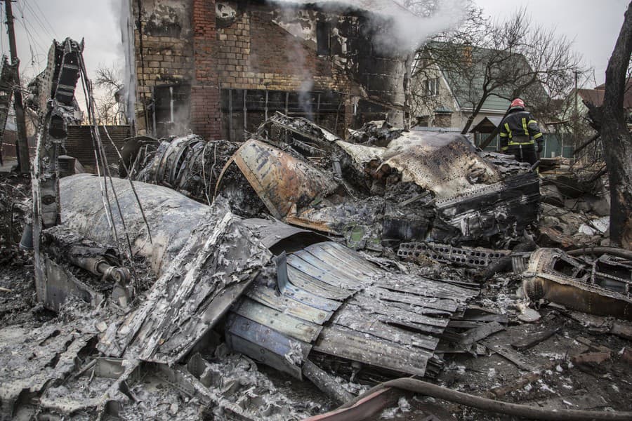 Ukrajinský hasič prechádza medzi fragmentmi zostreleného lietadla v Kyjeve