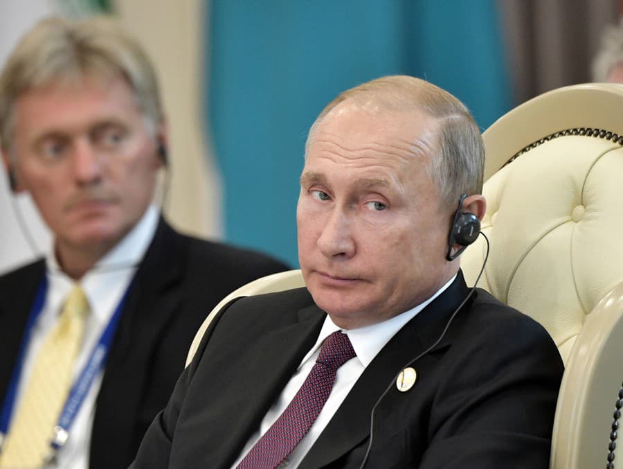 Vladimír Putin, v pozadí Dmitrij Peskov
