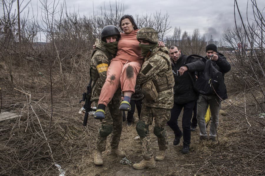Ukrajinskí vojaci pomáhajú zranenej žene.