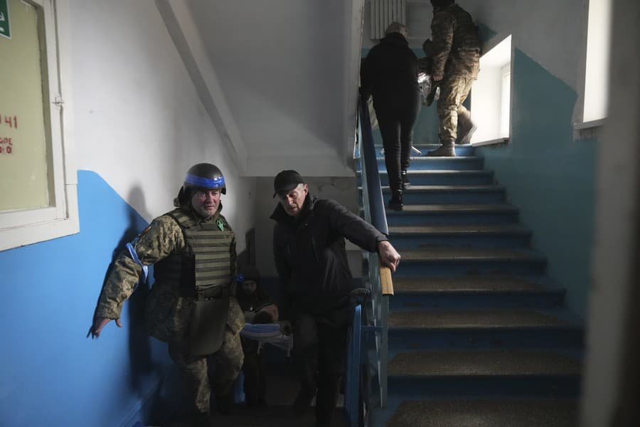 Ukrajinský vojak pomáha niesť človeka zraneného ostreľovaním v nemocnici v Mariupole
