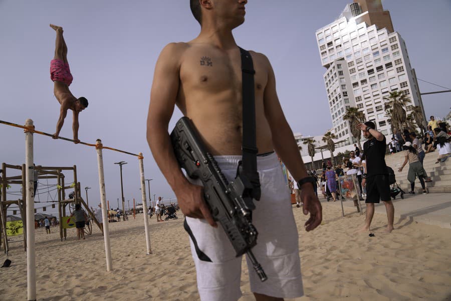 Izraelský vojak mimo službu nesie svoju pušku na pláži v Tel Avive v sobotu 2. apríla 2022. Izraelské bezpečnostné sily sú po nedávnych smrteľných útokoch v stave najvyššej pohotovosti.
