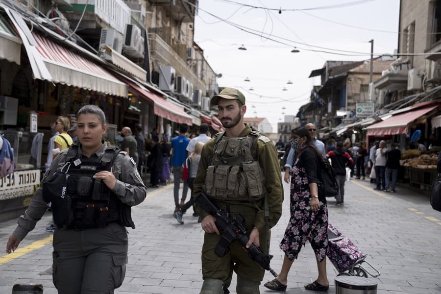 Dôstojníčka izraelskej pohraničnej polície vľavo hliadkuje so svojím armádnym náprotivkom na trhu Mahane Yehuda v Jeruzaleme v rámci sprísnených bezpečnostných opatrení, v nedeľu 3. apríla 2022. Napätie v posledných dňoch prudko vzrástlo po tom, čo palestínski útočníci zabili 11 Izraelčanov pri samostatných útokoch po celej krajine.