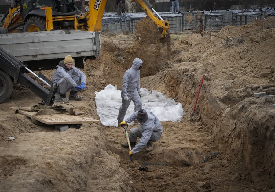 Muži v ochranných výstrojoch exhumujú telá civilistov zabitých počas ruskej okupácie v Buči