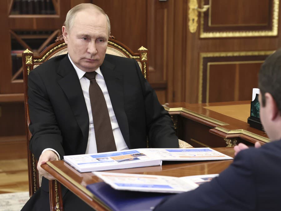 Ruský prezident Vladimir Putin sa musí držať stola pri jednom zo svojich verejných stretnutí. 