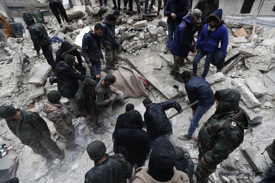 Pracovníci sýrskej civilnej obrany a členovia bezpečnostných síl prehľadávajú ruiny zrútených budov