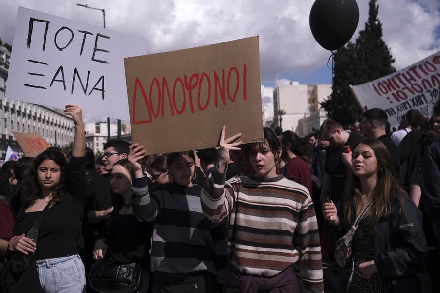 Ľudia držia transparenty s nápismi „Vrahovia“, v strede a „Už nikdy viac“, počas protestu pred gréckym parlamentom v Aténach v Grécku, v nedeľu 5. marca 2023.