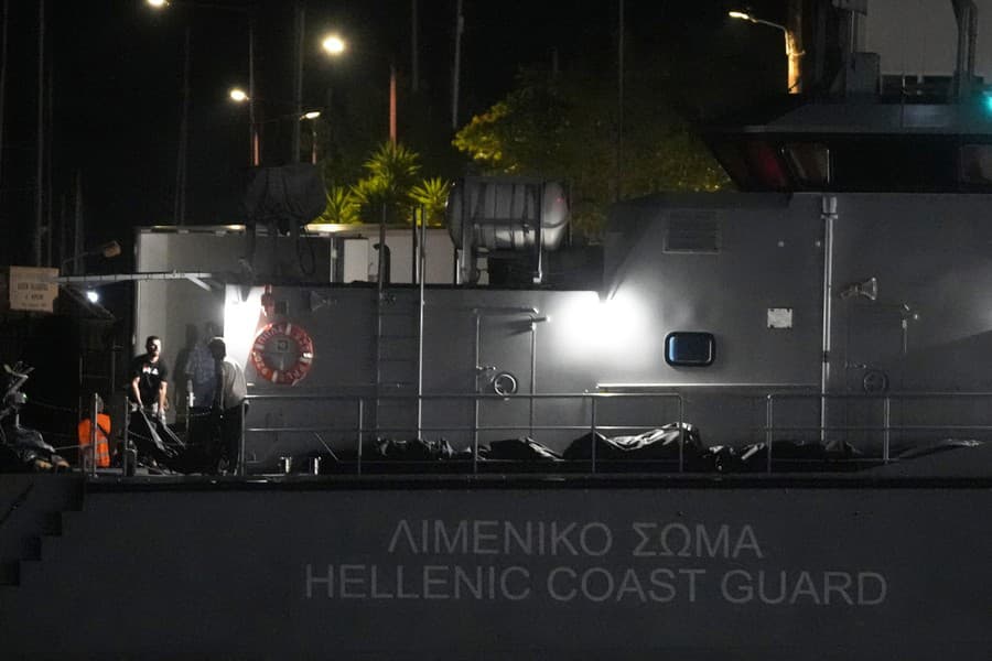 Záchranári prevážajú telá z plavidla pobrežnej stráže do chladiarenského auta v prístave v meste Kalamata.