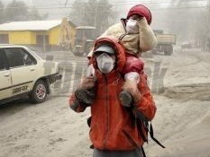 Muž s dieťaťom v ochranných rúškach kráčajú po ceste pokrytej sopečným prachom z čilského vulkánu Puyehue-Cordón Caulle