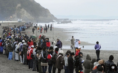 Ľudia sa držia za ruky a modlia za obete pri pobreži Iwaki vo Fukušime
