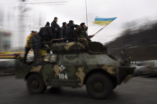 Demonštranti sa vezú na obrnenom vozidle v centre Kyjeva.