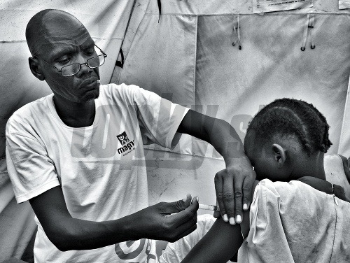 MAGNA pracovník v utečeneckom tábore v Jube, Južný Sudán, očkuje dieťa. Táto fotografia sa stala hlavným vizuálnym motívom podujatia.