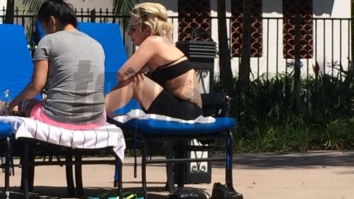 Pribratá Lady Gaga sa slní pri bazéne a schováva faldy na bruchu.