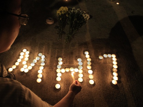 Muž v Kuala Lumpur zapaľuje sviečky na znak úcty voči obetiam pádu malajzijského lietadla.