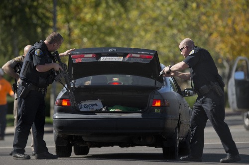 Policajti prehľadávajú auto pri pátraní po podozrivom
