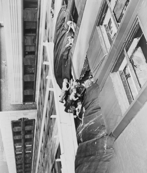 Robotníci zakrývajú dieru medzi 78. a 79. poschodím plachtou