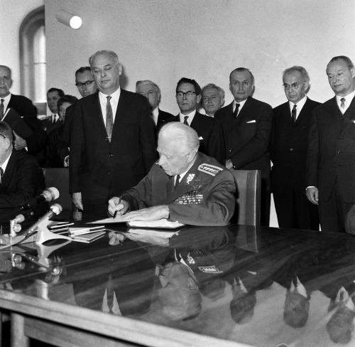Prezident Ludvík Svoboda podpisuje ústavný zákon o federácii na Bratislavskom hrade, vpravo A. Dubček, druhý sprava podpredseda československej vlády Gustáv Husák, 29. október 1968.