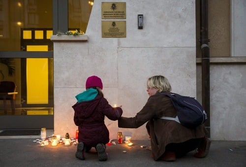 Matka s dcérkou zapaľujú sviečky pred belgickou ambasádou v Maďarsku.