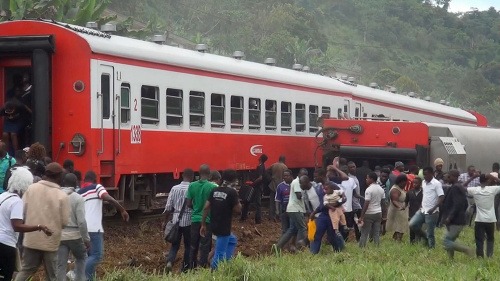 Na snímke ľudia kráčajú okolo vykoľajeného vlaku v kamerunskom meste Eséka 