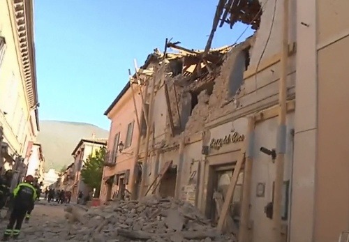 Hasiči pred zničenou budovou po zemetrasení v talianskej Norcii.